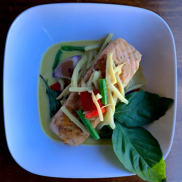 Ddee Thai's salmon in green curry with vegetables and basil, presented in a white bowl.